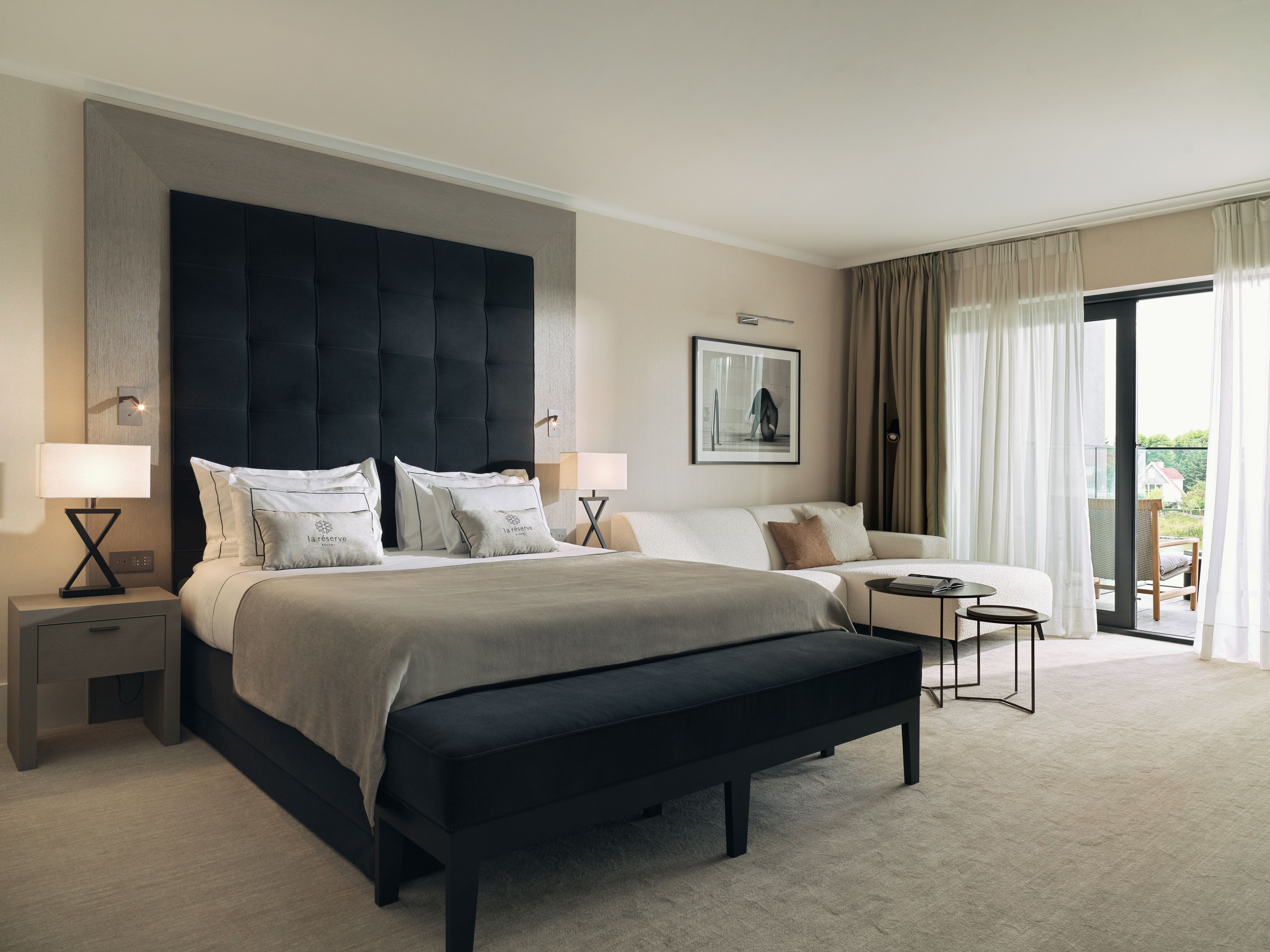Hotelkamer La Réserve Resort, een junior suite met balkon en zetel en ecru boucléstof met ligdeel 